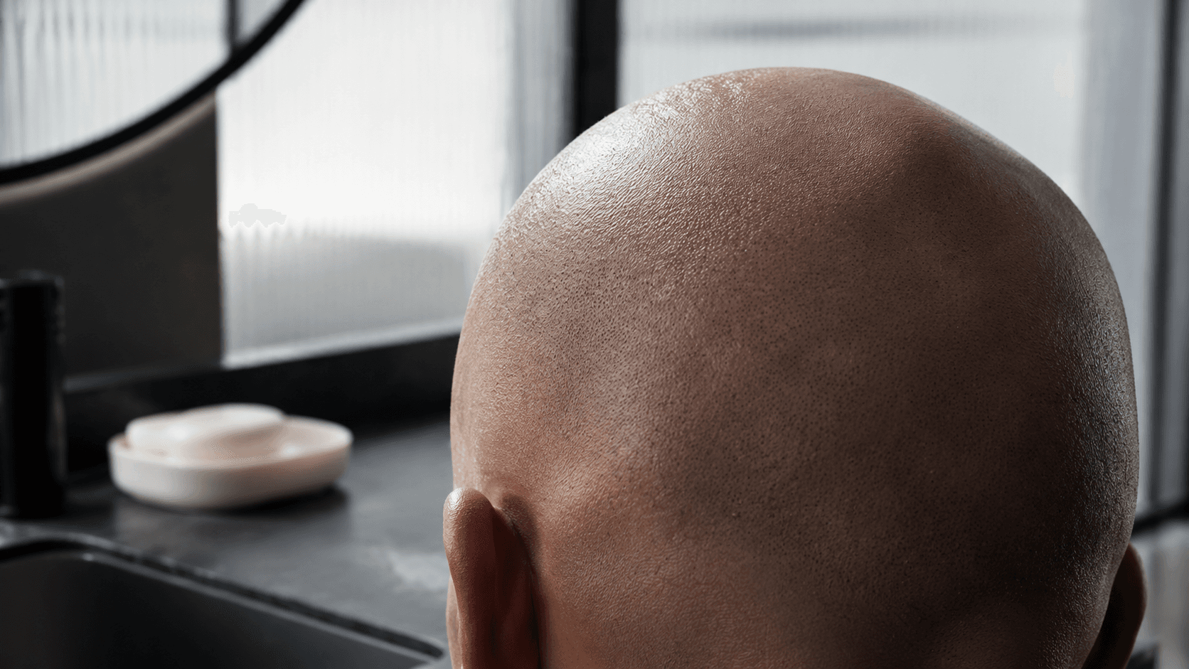 Man applying lightweight hydration to a freshly shaved scalp for lasting comfort